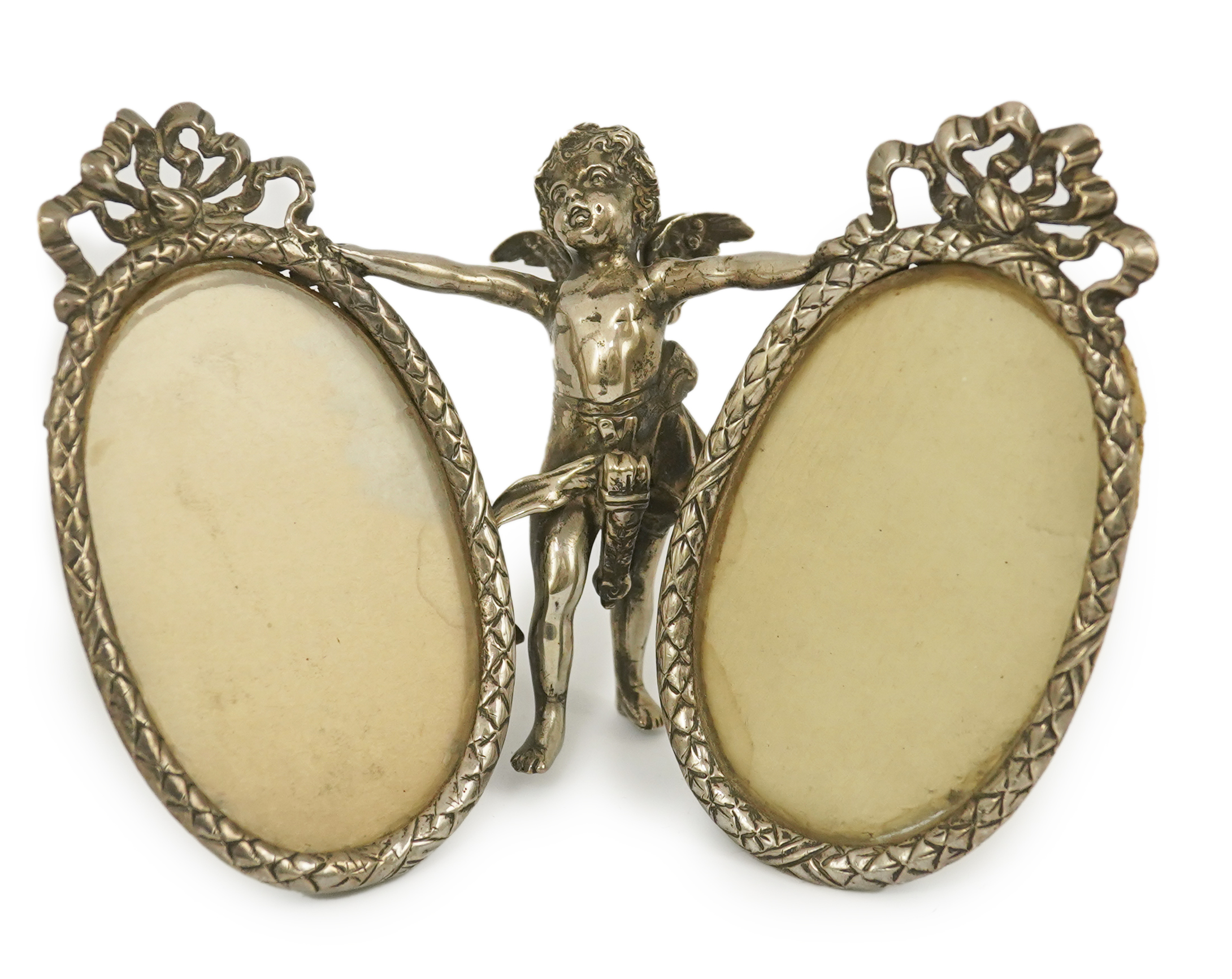 A late 19th century Hanau silver double oval photograph frame, supported by central figure of Cupid, by Berthold Muller